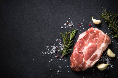Çiğ et. Siyah arka planda baharatlı taze domuz bifteği. Kopyalama alanı olan üst görünüm.