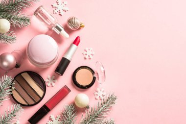 Make up products with christmas decorations at pink. Flat lay image with copy space. Christmas sale and christmas gift concept.