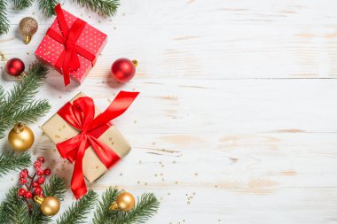 Kırmızı kurdeleli ve Noel süslemeli Noel hediyesi kutusu. Kopya alanı olan beyaz ahşap masadaki üst görünüm.