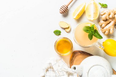 Limonlu zencefil çayı ve malzemeli cam bardakta nane. Metin için boşluk olan beyaz tabloda en üstteki görünüm.