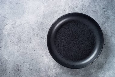 Gri taş masadaki siyah tabak. Kopyalama alanı olan üst görünüm.