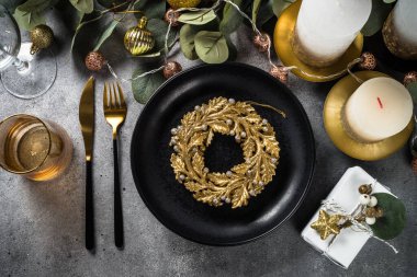 Noel sofrasında okaliptüs yaprakları ve altın süslemeler. Taş masadaki üst görünüm.