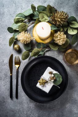 Siyah tabaklar, mumlar, okaliptüs yaprakları ve altın süslemeler. Taş masadaki üst görünüm.