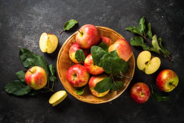 Elmalar. Siyah taş masadaki sepetin içinde taze kırmızı elmalar. Üst görünüm.