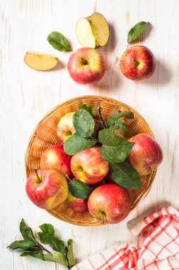 Elmalar. Beyaz ahşap masadaki sepetin içinde taze kırmızı elmalar. Üst görünüm.