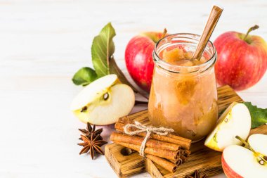 Beyaz arka planda elma reçeli, baharatlar ve taze elmalar..