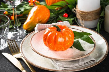 Table setting with plate, pumpkin and candles at wooden table. Autumn table decorations. Thanksgiving food, dinner concept.