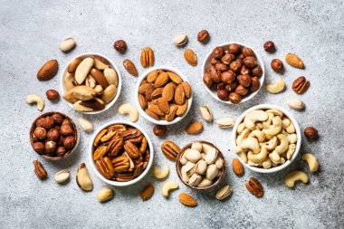 Fındık çeşitleri kaselerde. Kaju, fındık, ceviz, badem, Brezilya fındığı ve fıstık. Işık taşı masadaki en üst görünüm.