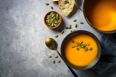 Kavanozda balkabağı çorbası ve taş masada siyah kase. Kopyalama alanı olan üst görünüm.