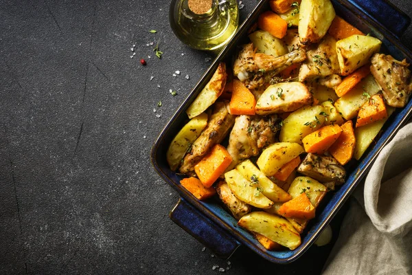 stock image Chicken meat with pumpkin and potato in baked dish at dark table. Top view with copy space.