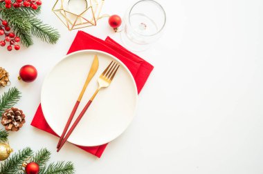 Beyaz arka planda tabak, çatal bıçak ve Noel süslemeleri olan bir Noel masası. Noel yemeği, tatil masası. Üst görünüm.