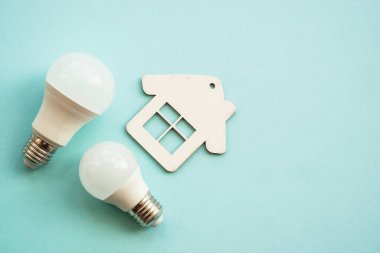 Elektrik tasarrufu. Faturaları ödüyorum. LED lamba, fişi olan kablo ve renkli arka planda ev.