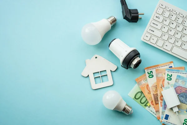 stock image Utility payments. Electricity and heating savings concept. Led lamp, thermostat, calculator and electric cable at blue. Flat lay image with space for text.