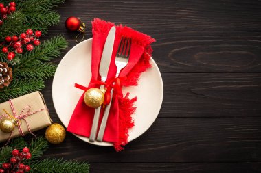 El sanatları tabağı, çatal bıçak takımı, hediye kutusu ve koyu ahşap arka planda noel süslemeleri. Kopyalama alanı olan üst görünüm.
