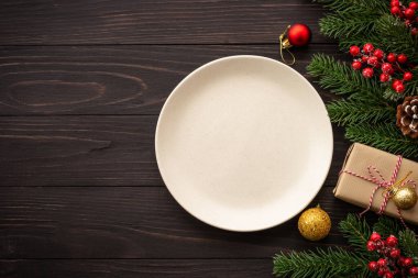 Noel yemeği, Noel sofrası yemeği, el sanatları tabağı ve karanlık ahşap arka planda noel süslemeleri. Kopyalama alanı olan üst görünüm.