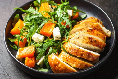 Balkabaklı tavuk salatası, mavi peynir ve siyah tabakta roka. Dash diyet tarifi.