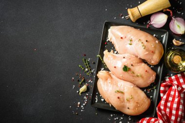 Siyah arka planda yemek pişirmek için malzemeli tavuk göğsü. Kopyalama alanı olan üst görünüm.