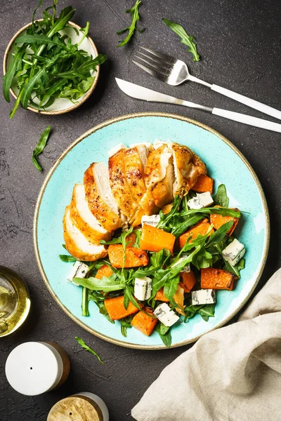 Warm salad with baked chicken breast, pumpkin, blue cheese and arugula. Dash diet, keto diet meal. Top view, vertical.