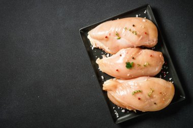 Siyah arka planda baharatlı tavuk göğsü. Çiğ et pişmeye hazır. Kopyalama alanı olan üst görünüm.