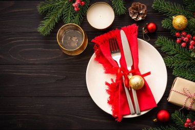 El sanatları tabağı, çatal bıçak takımı, hediye kutusu ve koyu ahşap arka planda noel süslemeleri. Kopyalama alanı olan üst görünüm.