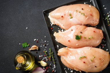 Siyah arka planda yemek pişirmek için malzemeli tavuk göğsü. Kopyalama alanı olan üst görünüm.