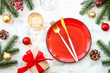 El işi tabağı, çatal bıçak takımı, hediye kutusu ve beyaz ahşap masada noel süsleri. En üst görüntü.