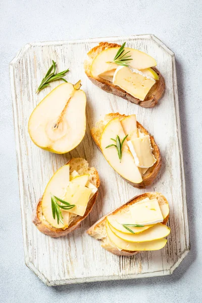 Beyaz masada armutlu, peynirli ve ballı tost. Sağlıklı atıştırmalıklar ya da kahvaltı. Üst görünüm.