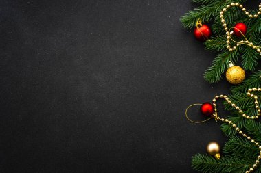 Noel arkaplanı düzdü. Siyah üzerine kırmızı ve altın bayram süslemeleri olan fidan ağacı.