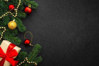 Noel arkaplanı düzdü. Şimdiki kutu, köknar ağacı ve siyah üzerine tatil süslemeleri..