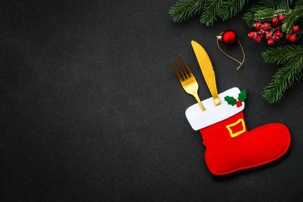 Christmas food, christmas table setting with cutlery and christmas decorations on black background. Flat lay with copy space.