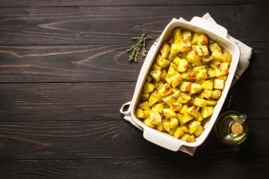 Koyu kırsal masada kekikli fırında patates. Vejetaryen yemeği. Kopyalama alanı olan üst görünüm.