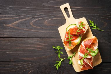 Aperatif crostini, krem peynirli sandviç, prosciutto, salatalık ve roka. Kopyalama alanı olan düz.