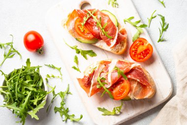 Aperatif crostini, krem peynirli sandviç, prosciutto, salatalık ve roka. Kopyalama alanı olan üst görünüm.