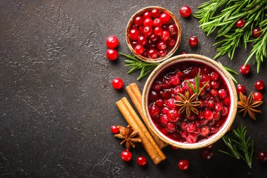 Biberiye ve baharatlı bir kasede kızılcık sosu. Siyah arkaplanda üst görünüm.