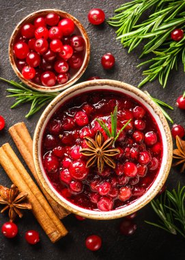 Biberiye ve baharatlı bir kasede kızılcık sosu. Siyah arkaplanda üst görünüm.