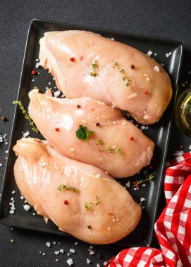 Siyah arka planda baharatlı tavuk göğsü. Çiğ et pişmeye hazır. Üst görünüm.