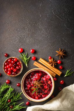 Biberiye ve baharatlı bir kasede kızılcık sosu. Siyah arkaplanda üst görünüm.