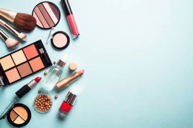 Make up professional cosmetics on blue background. Powder, lipstick, shadow, brushes. Flat lay with copy space.