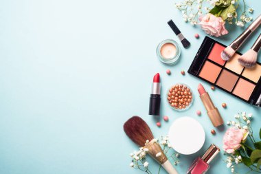 Make up products on blue background. Cream, powder, shadow, brushes. Flat lay image with copy space.