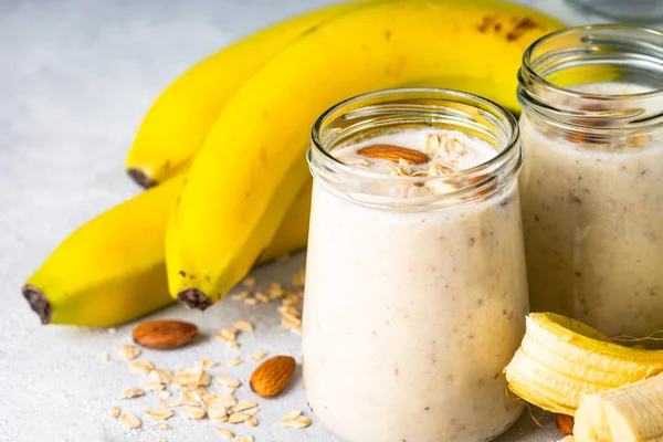 Almond banana smoothie with oat flakes in glass. Close up image.