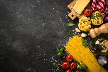 Siyahların İtalyan yemekleri geçmişi. Çiğ makarna, taze domates, zeytinyağı, baharat ve fesleğen. Kopyalama alanı olan üst görünüm.