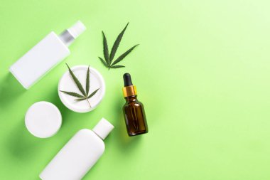 Esrar kozmetik ürünleri. Doğal kozmetik. Krema, sabun, serum ve diğerleri. Fotokopi alanı olan yeşil arkaplan üzerine düz resim koy.