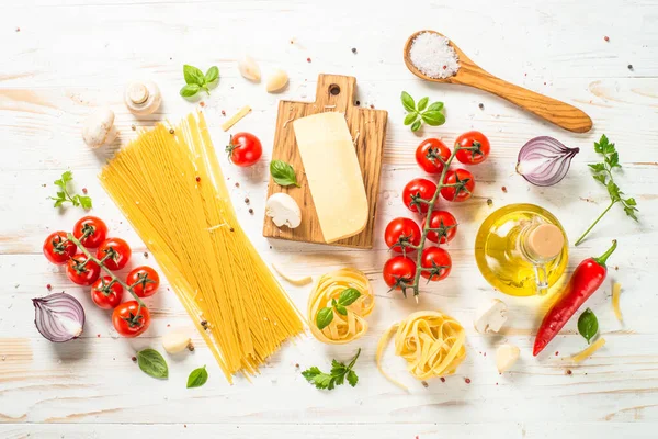 Italian food background on white kitchen table. Ingredients for cooking pasta. Top view with copy space.