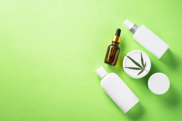 Cannabis cosmetic products. Natural cosmetic. Cream, soap, serum and others. Flat lay image on green background with copy space.