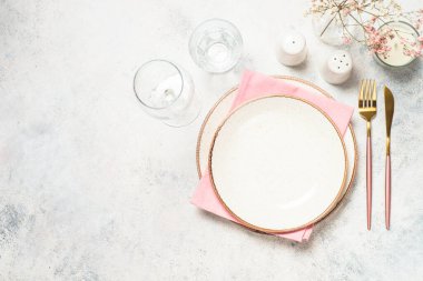 Tabaklı masa, çiçekler ve çatal bıçak takımı beyaz mutfak masasında. Bahar ya da yaz sofrası. Kopyalama alanı olan üst görünüm.