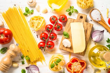 İtalyan yemek geçmişi beyaz mutfak masasında. Makarna pişirmek için gerekli malzemeler. Kopyalama alanı olan üst görünüm.