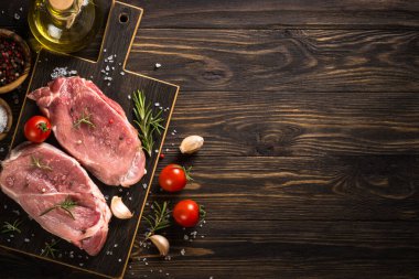Taze et biftekleri, ahşap arka planda baharatlı ve otlu domuz bifteği. Kopyalama alanı olan üst görünüm.