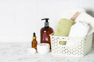 Banyodaki spa ürünleri. Beyaz banyoda bir şişe sabun, kozmetik ve beyaz havlular..