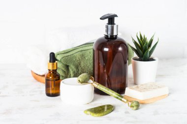 Banyo aksesuarları. Spa tedavi ürünleri. Banyoda bir şişe sabun, krema, serum ve havlu var..