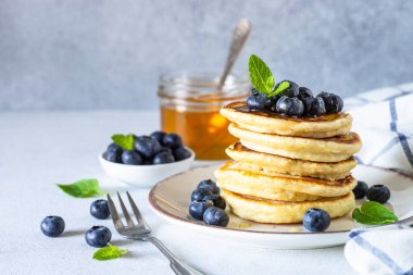 Beyaz masada taze yaban mersinli krep ve bal..